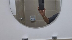 Ein Badezimmer mit rundem Spiegel, einem Handspiegel und einer Handbrause.