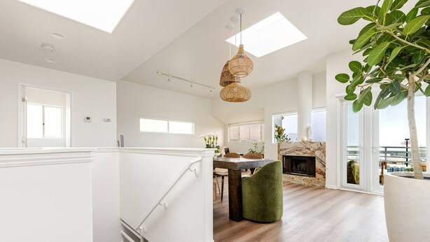 A spacious living area with a fireplace, wooden flooring, and a dining table.