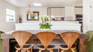 A modern kitchen with white cabinets, a central island, and a dining area with wooden chairs and a table.