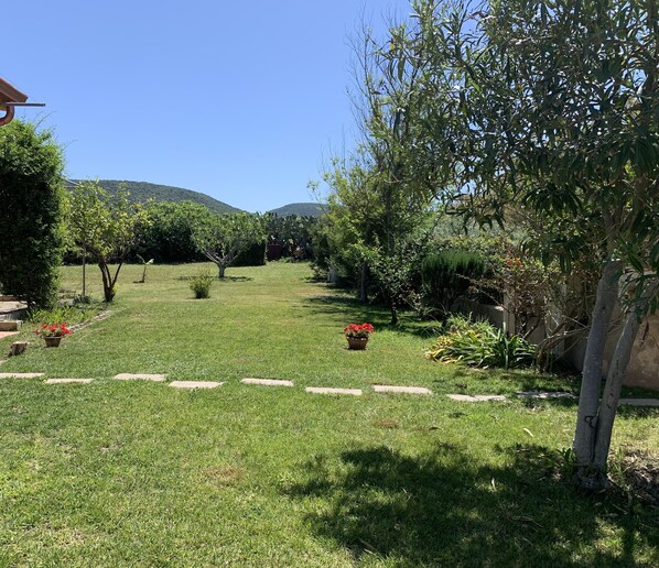 Un jardin bien entretenu, avec un chemin bien défini, diverses plantes et une vue sur des collines lointaines.