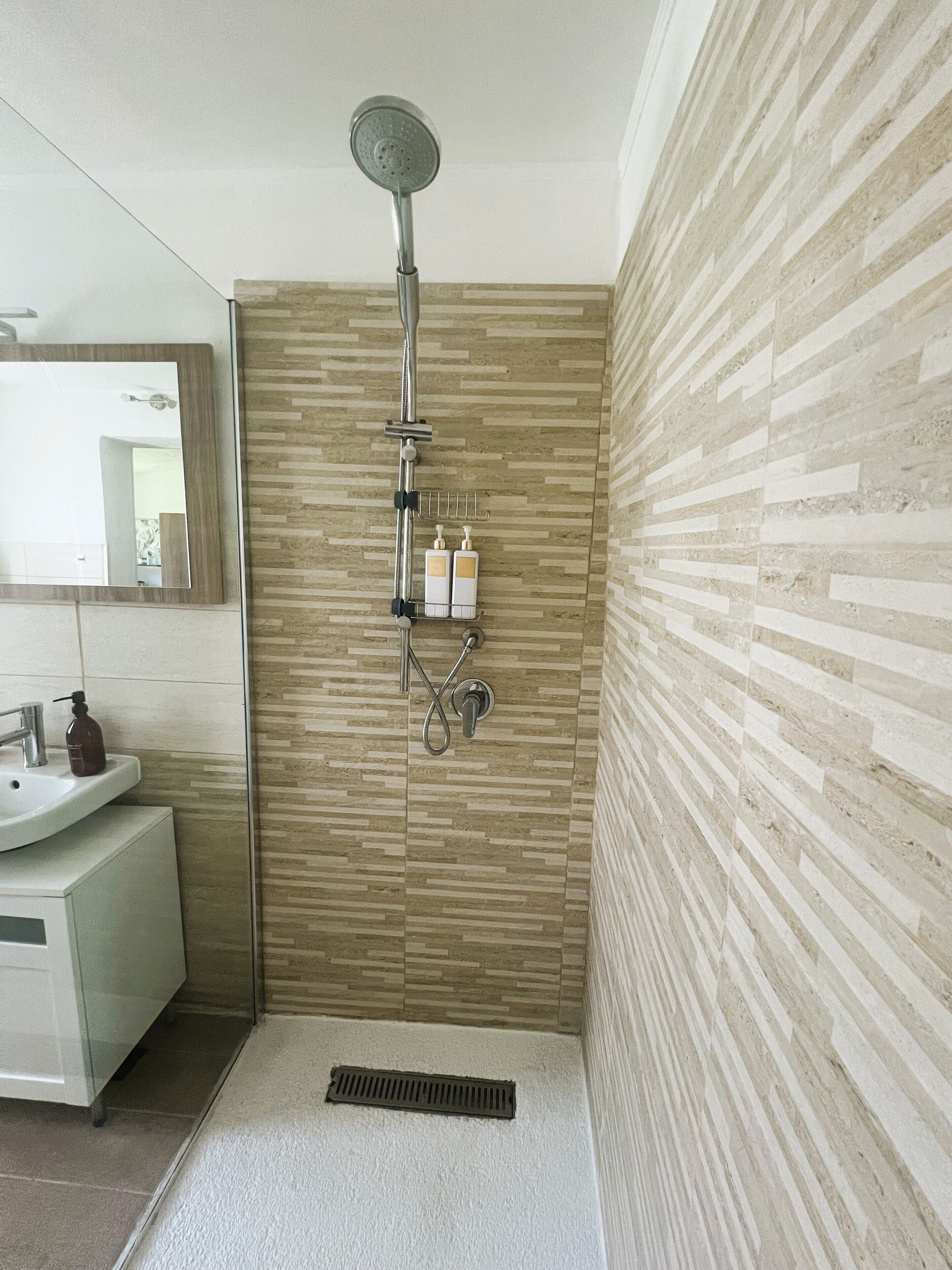 Un baño moderno con ducha, lavamanos y espejo.