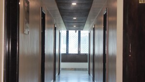 A corridor with a metal floor, wooden doors, and a window with a metal grid. - Hotel Planet Four (Mawal)