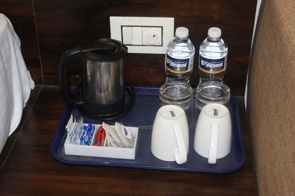 A tray with a coffee pot, two water bottles, and two white mugs on a wooden surface. - Hotel Planet Four (Mawal)