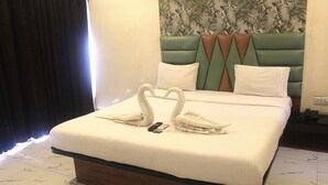 A neatly made bed with a headboard, pillows, and a towel arrangement. - Hotel Planet Four (Mawal)
