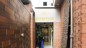 A reception area with a sign labeled "RECEPTION" and a potted plant outside. - Hotel Planet Four (Mawal)