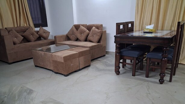 A living room with a sofa set, a glass coffee table, and a wooden dining table with chairs.