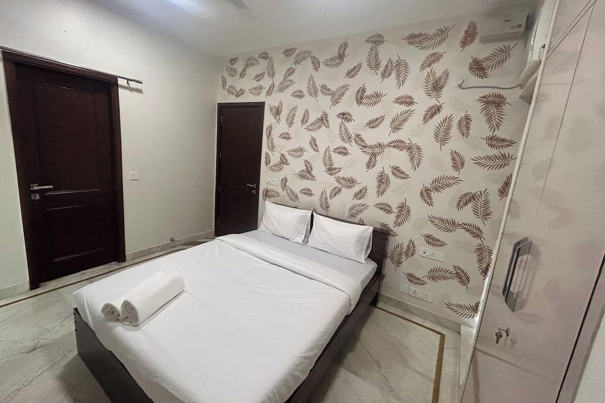 Un dormitorio con una cama, dos puertas y un muro con diseño de hojas.