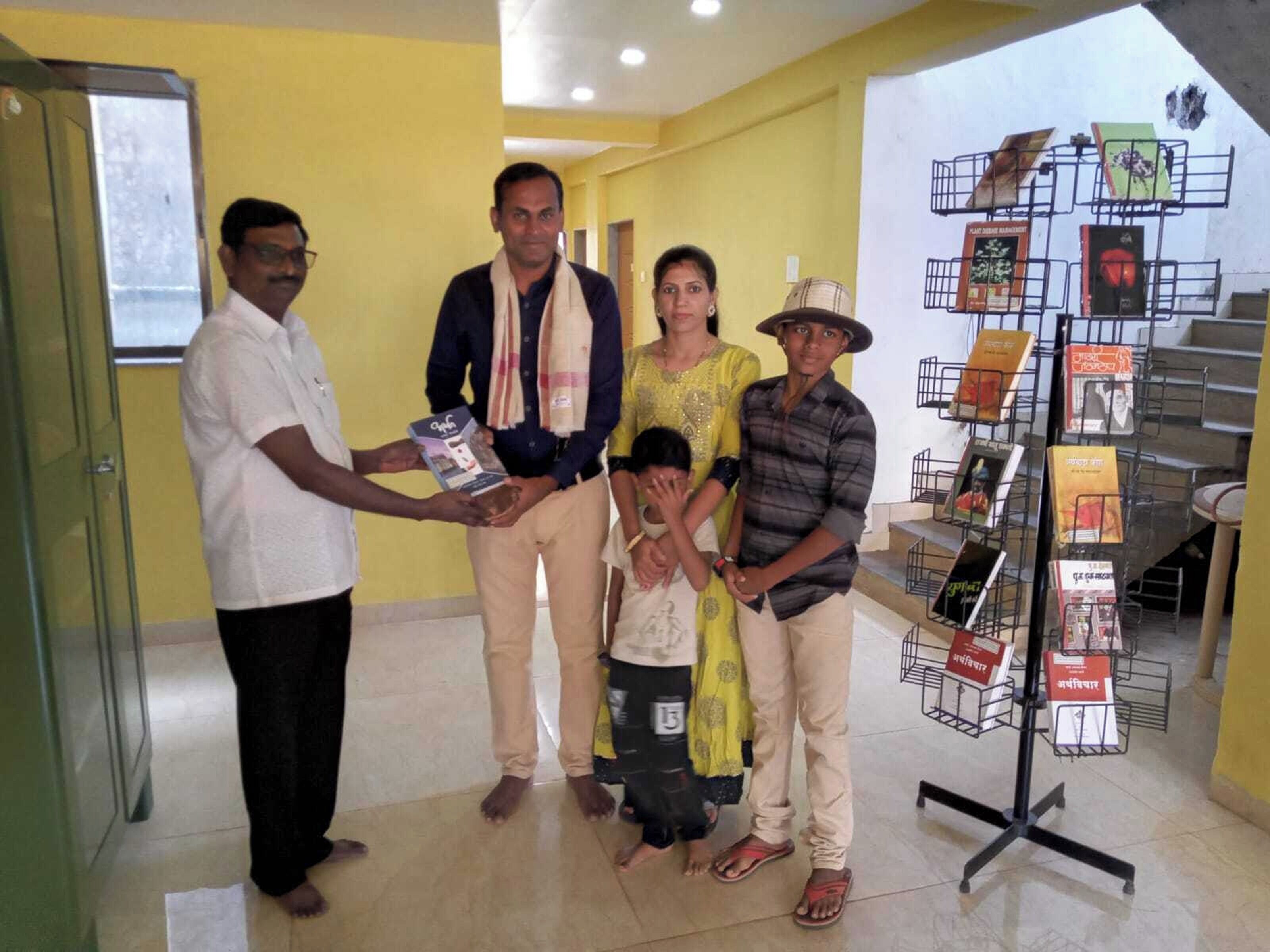 A group of people in a room with a display stand of books and a projector screen.