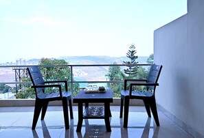 A balcony with two chairs and a table, overlooking a scenic view of hills and trees. - Hotel Sunrise, Panchgani (Bhilar)