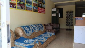 A reception area with a sofa, chairs, a wall with tourist information posters, and a CCTV sign. - Hotel Sunrise, Panchgani (Bhilar)