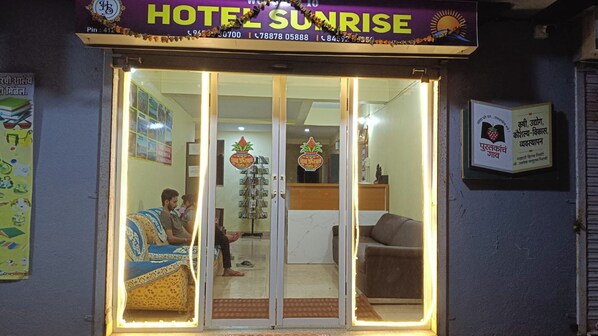 A hotel entrance with a glass door, a reception desk inside, and a signboard above the door. - Hotel Sunrise, Panchgani (Bhilar)