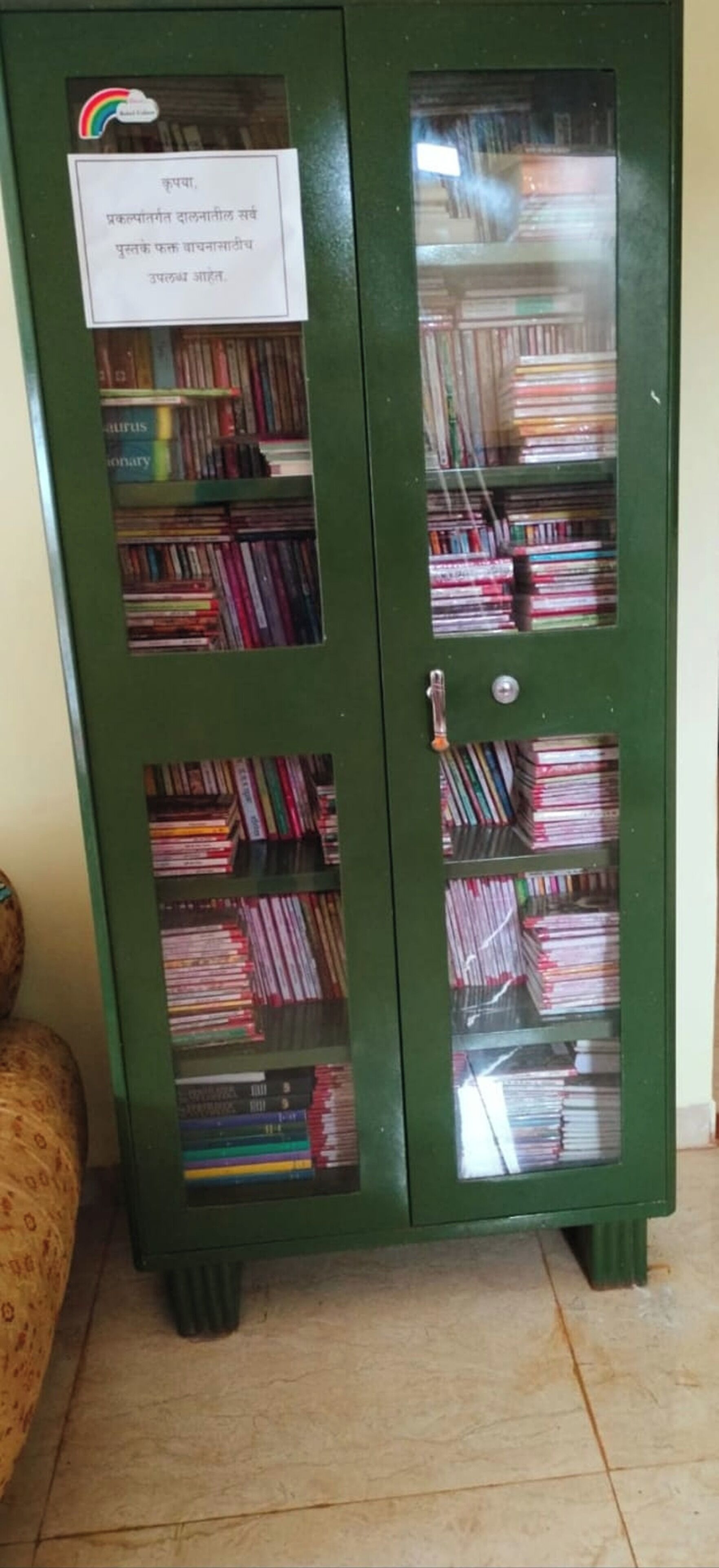 Une armoire métallique verte avec des portes en verre, contenant des livres et une affiche avec du texte.