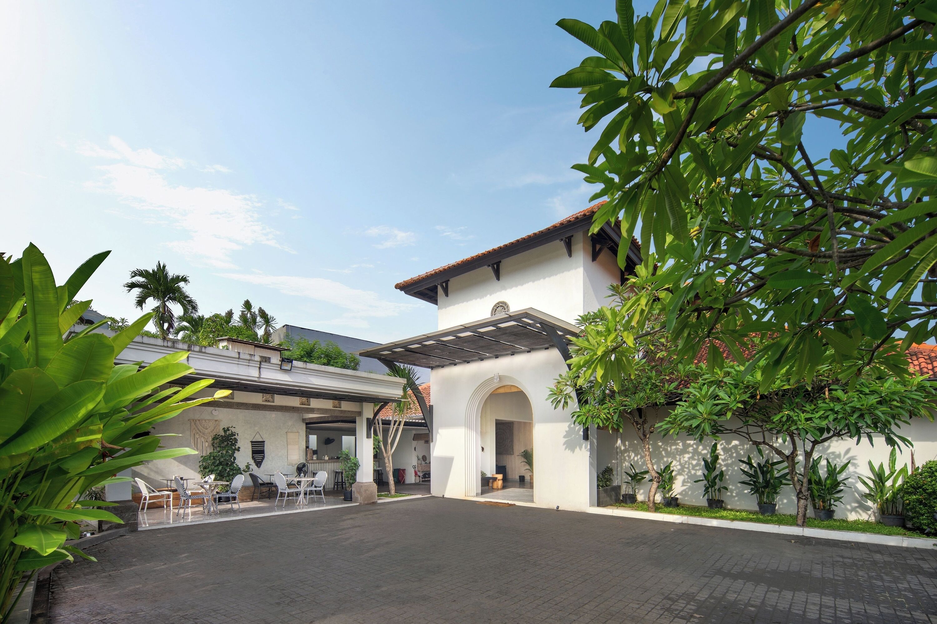 A courtyard with a white building, a covered seating area, and potted plants.