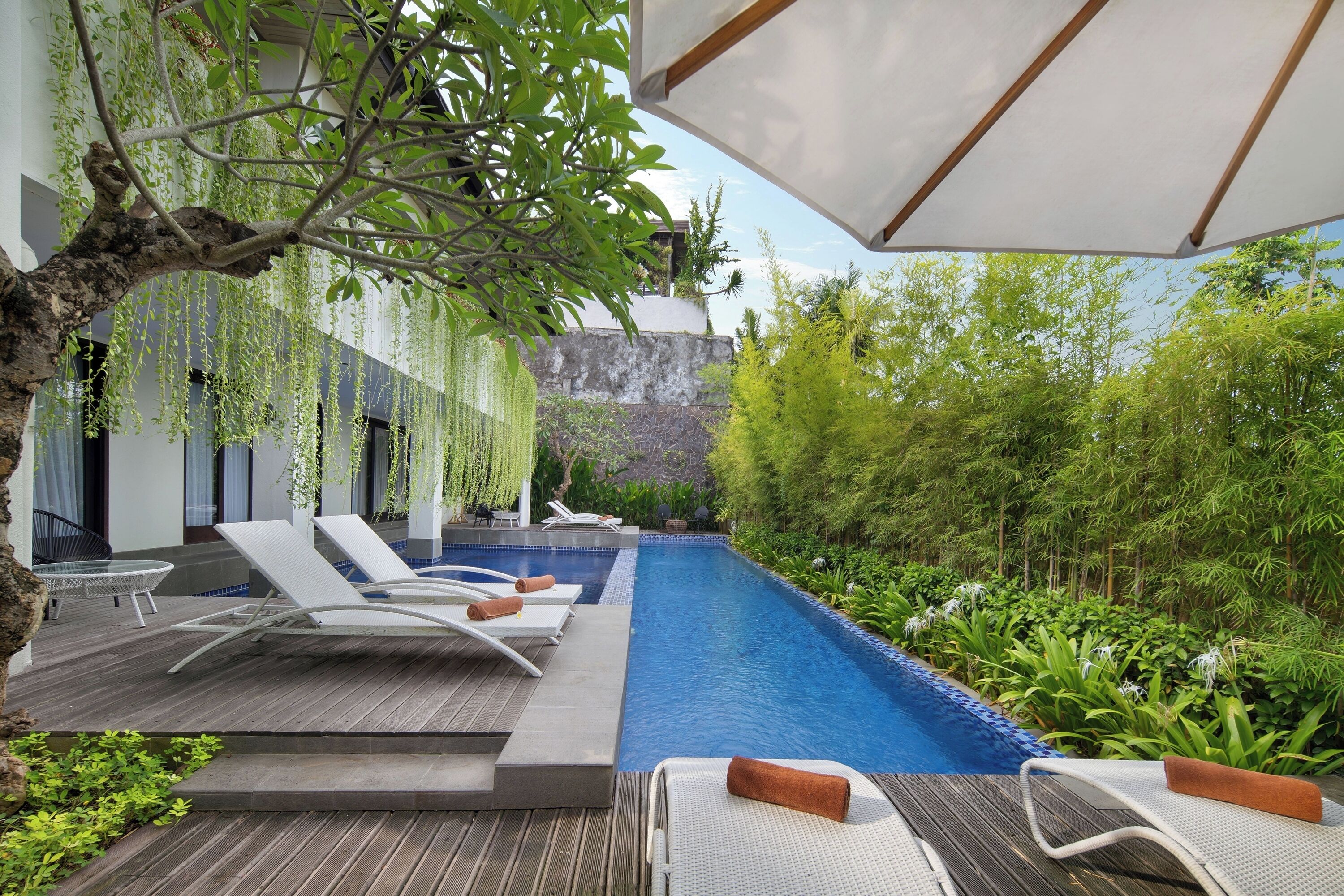 A poolside area with lounge chairs, a wooden deck, and a hanging plant.