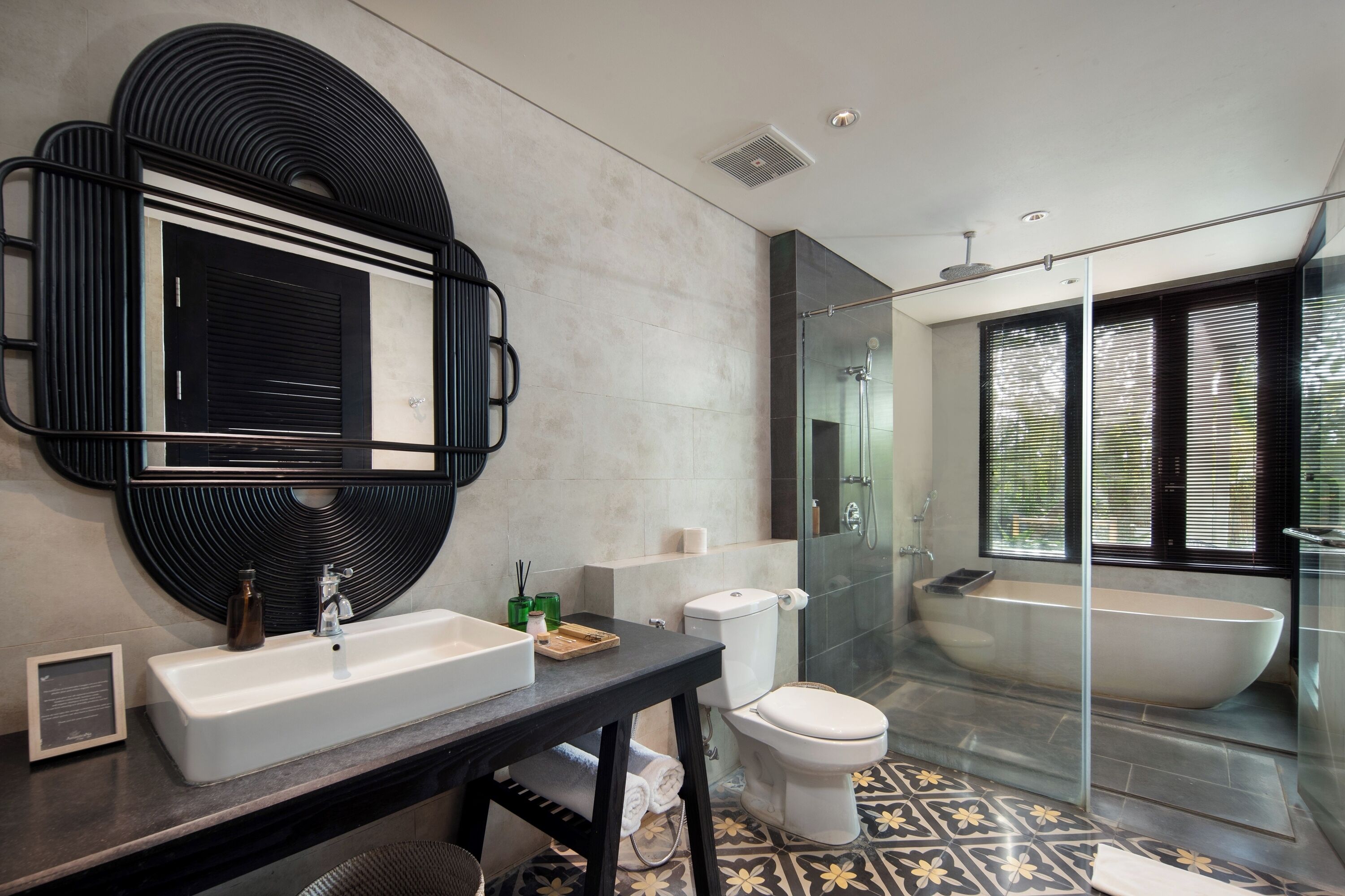 A modern bathroom with a large mirror, a sink, a toilet, and a glass-enclosed shower area.