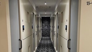 Ein Hotelkorridor mit Schließfächern an beiden Seiten und einem Schachbrettmuster-Teppich.