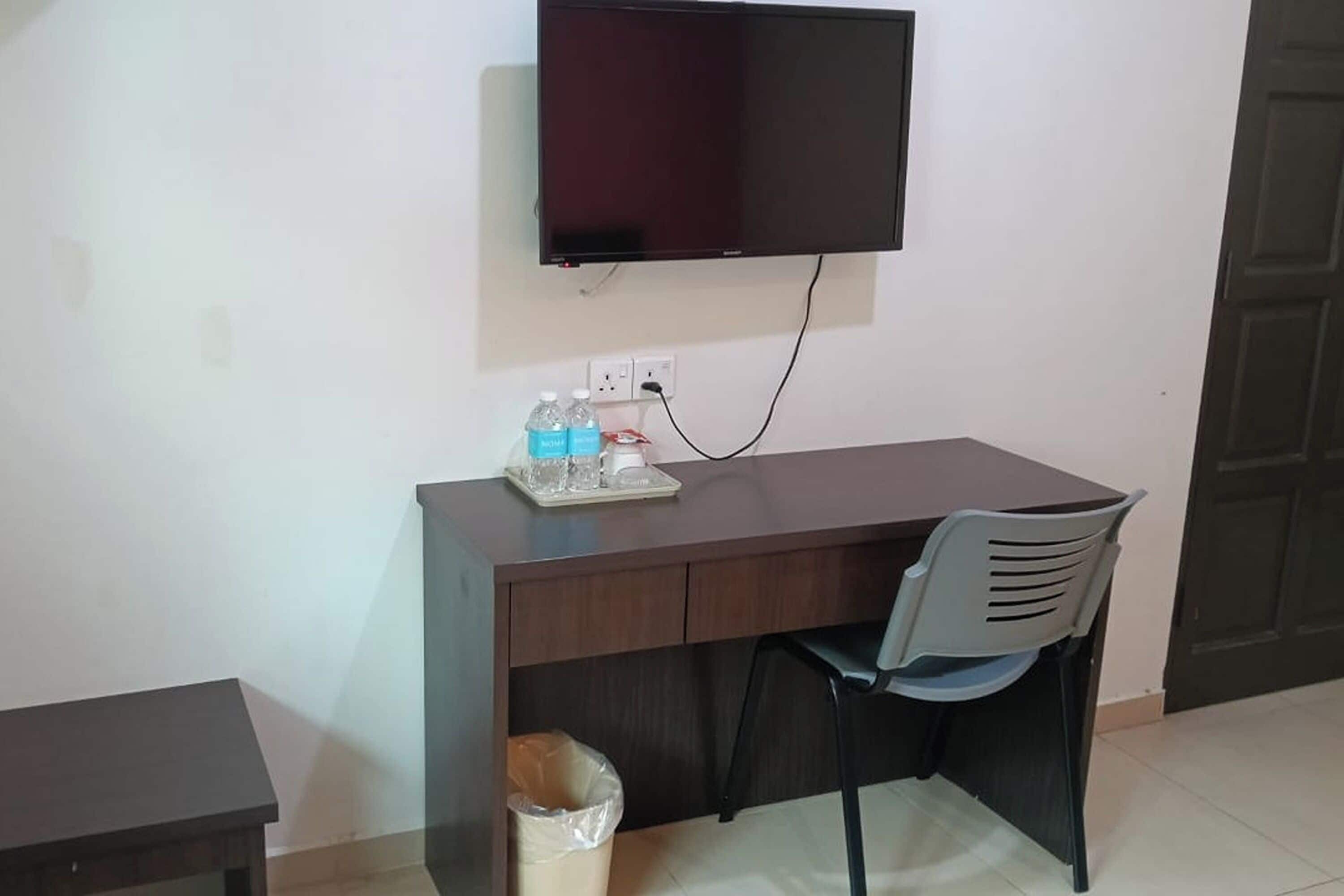 A small office space with a desk, chair, and a TV mounted on the wall.