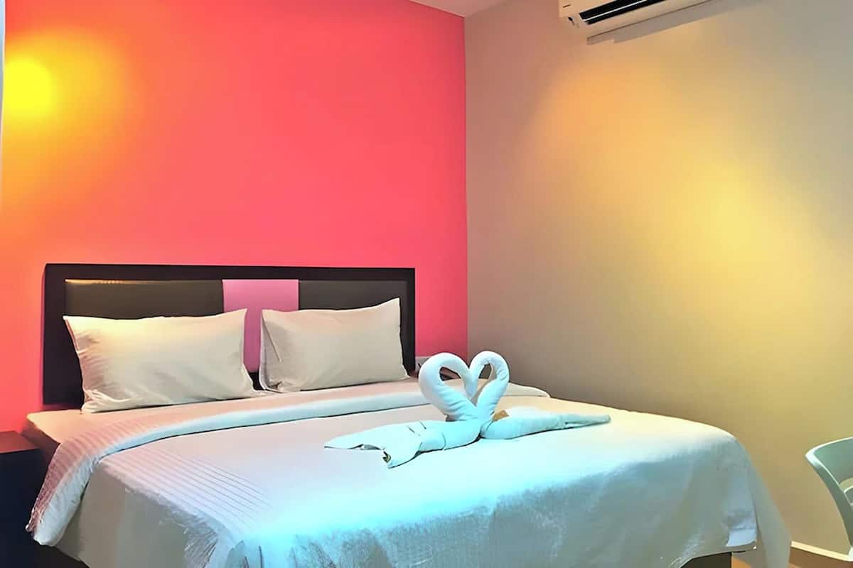 A hotel room with a bed, pillows, and a towel art arrangement.