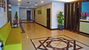 A hotel lobby with a yellow sofa, a geometric patterned floor, and potted plants. - Hotel City 88 Sdn Bhd [Batu Pahat] (Batu Pahat)