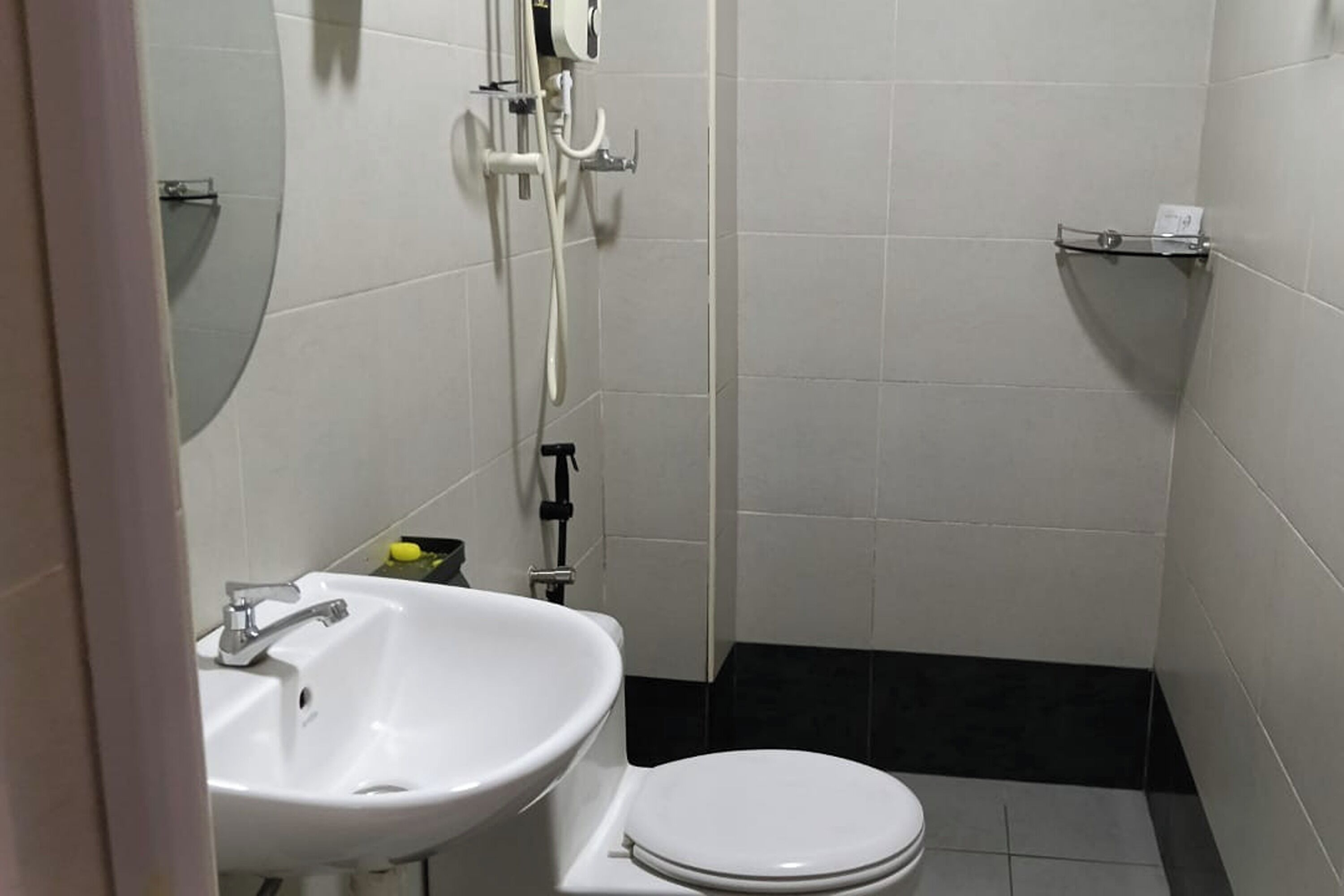 Een kleine, schone badkamer met een witte wastafel, toilet en douche.