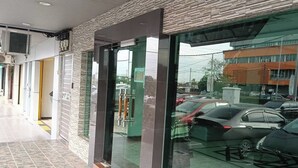 A modern building with a glass entrance, a tiled floor, and a parking area with cars. - Hotel City 88 Sdn Bhd [Batu Pahat] (Batu Pahat)