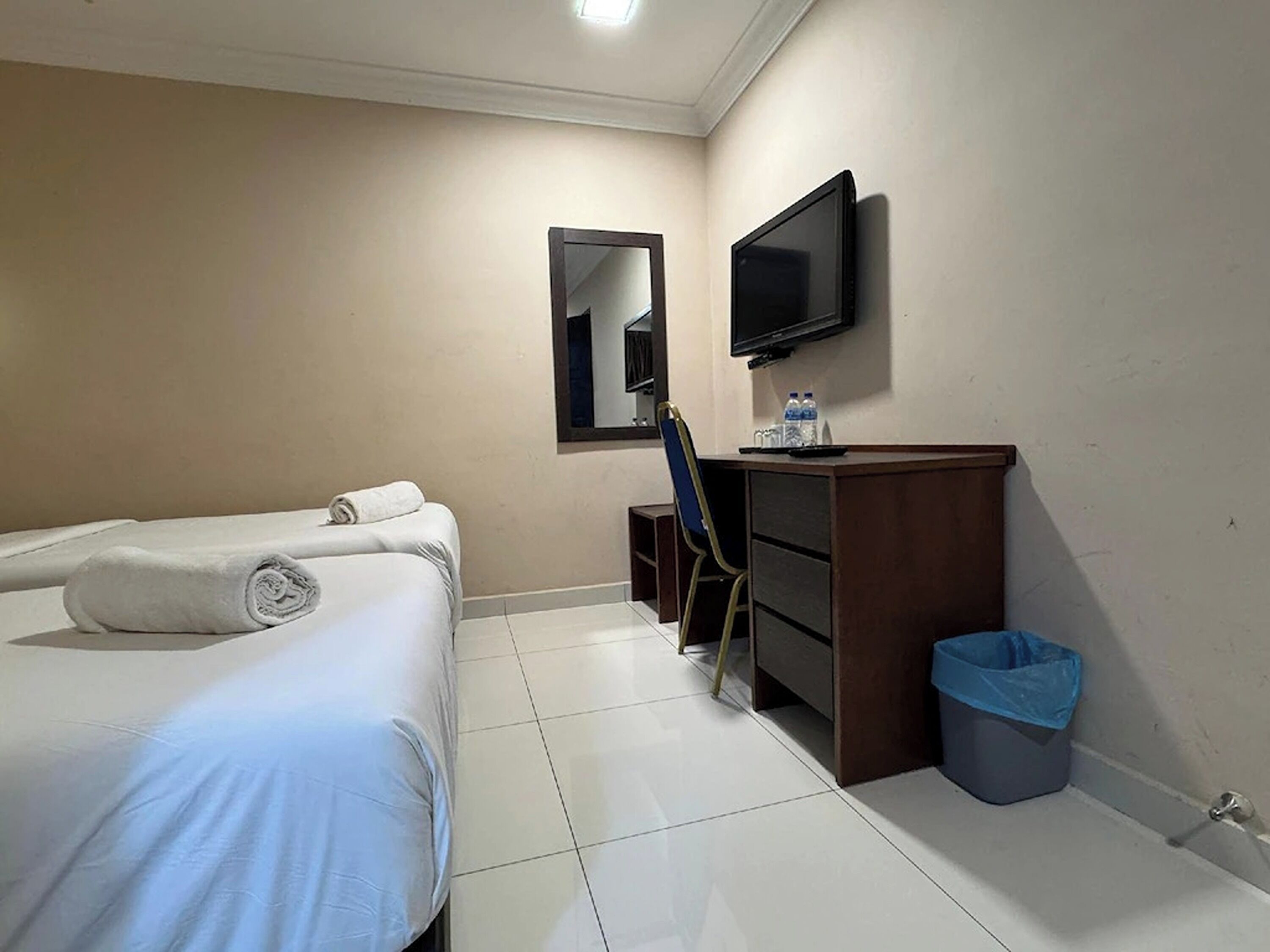 Une chambre d’hôtel équipée d’un lit, d’un bureau, d’une chaise, d’une télévision et d’une poubelle.