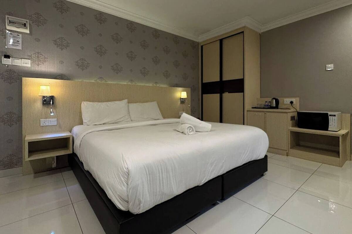 Camera d'hotel con un letto grande, abat-jour, un armadio e un forno a microonde.