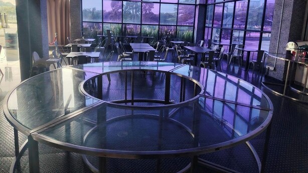 A modern restaurant with round tables and chairs, large windows with a view of trees and a purple sky. - Arafah Hotel Nilai (Nilai)