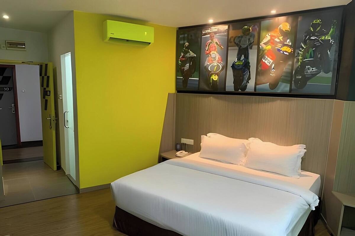 Ein Hotelzimmer mit einem großen Bett, einem Nachttisch, einem Telefon und einer Wandklimaanlage.