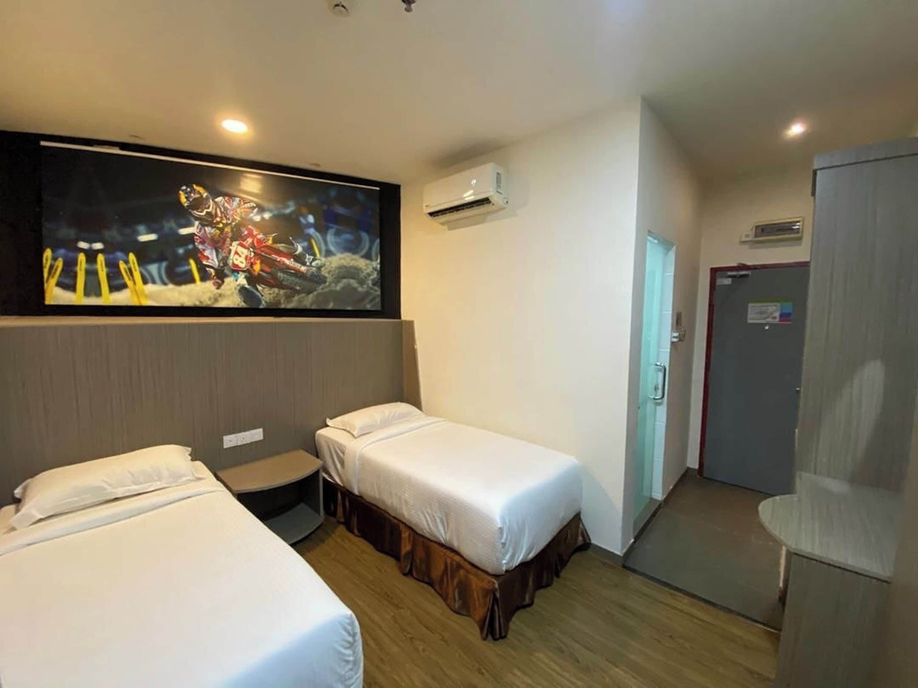 Habitación de hotel con dos camas, televisión, aire acondicionado y una puerta.