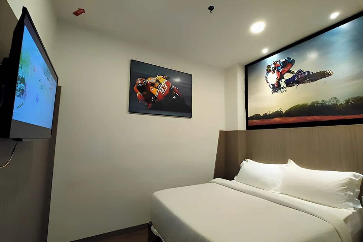Ein Hotelzimmer mit einem Bett, einem Flachbildfernseher und zwei großen Postern an den Wänden.