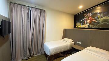A hotel room with two single beds, a TV mounted on the wall, and a large window with curtains.