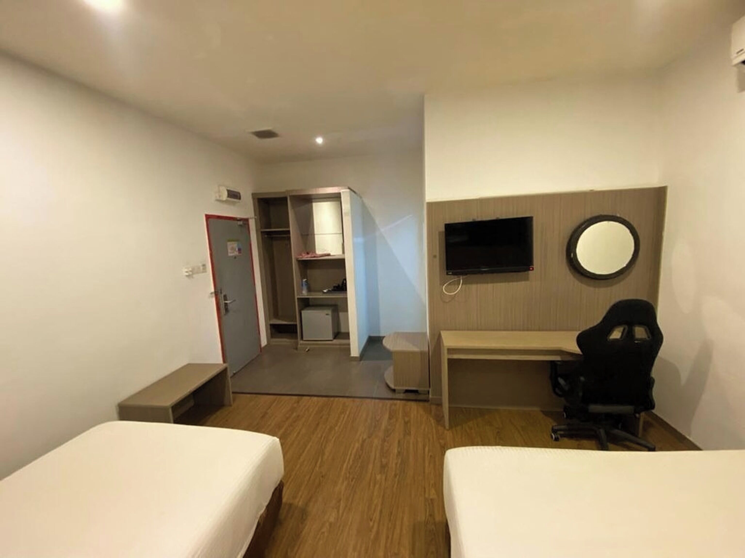 Habitación de hotel con dos camas, un escritorio, una silla, un televisor y un espejo.