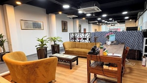 Un interior moderno con un sofá, sillones, una mesa de centro y un escritorio con una computadora.