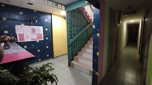 Ein Flur mit einer Treppe, einem Schwarzdbrett und einer Pflanze.