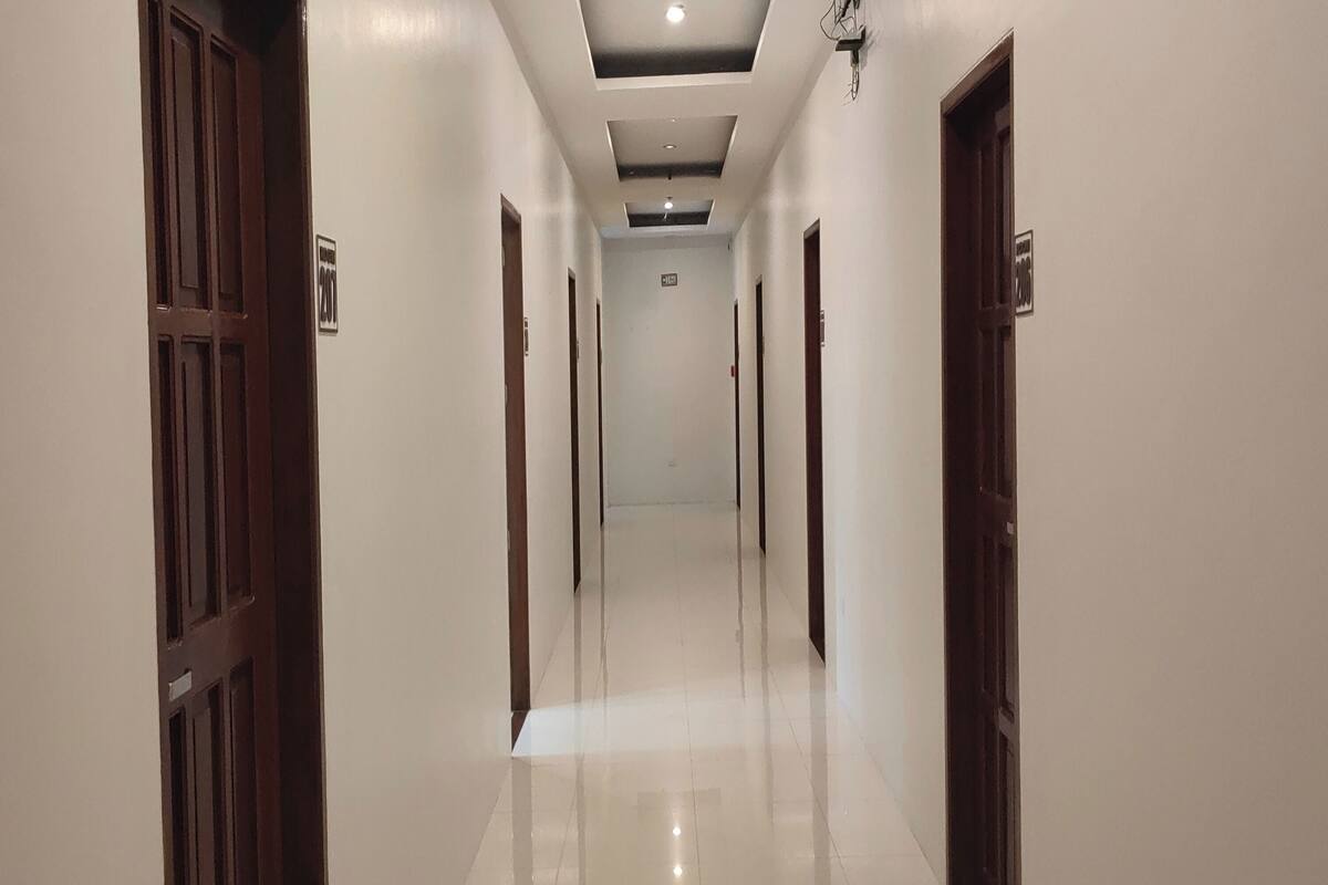 A long, narrow hallway with wooden doors on both sides and a tiled floor.