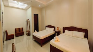 A hotel room with two beds, a sofa, a bedside table, and a ceiling light. - Isabelle Hotel (Puerto Princesa)