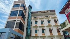A hotel with a sign reading "ISABELLE HOTEL" on a white building with brown accents and multiple windows. - Isabelle Hotel (Puerto Princesa)