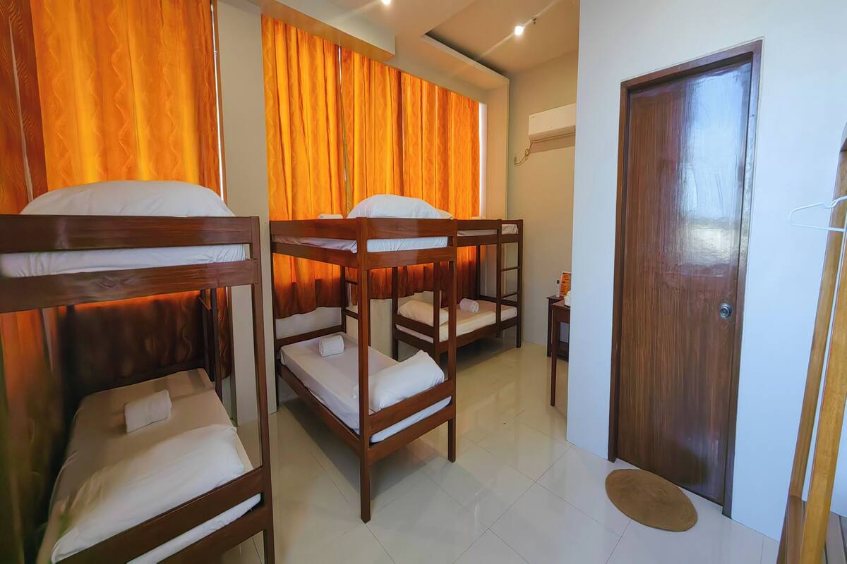 A room with bunk beds, a wooden door, and a small table with a bottle.
