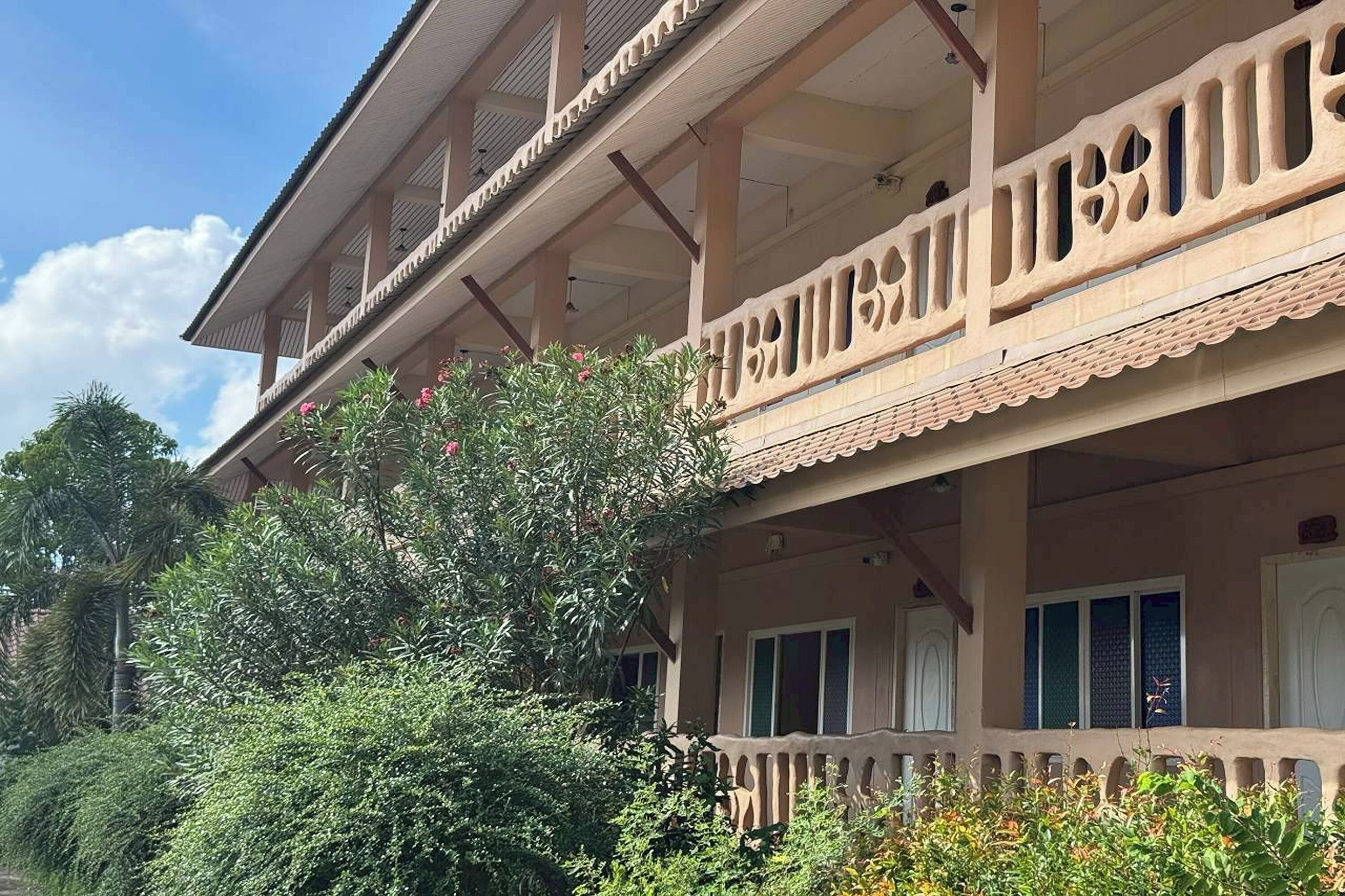 A two-story building with a balcony, surrounded by dense greenery.