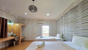 Une chambre d’hôtel avec deux lits, un bureau, une chaise, un luminaire suspendu et une fenêtre.