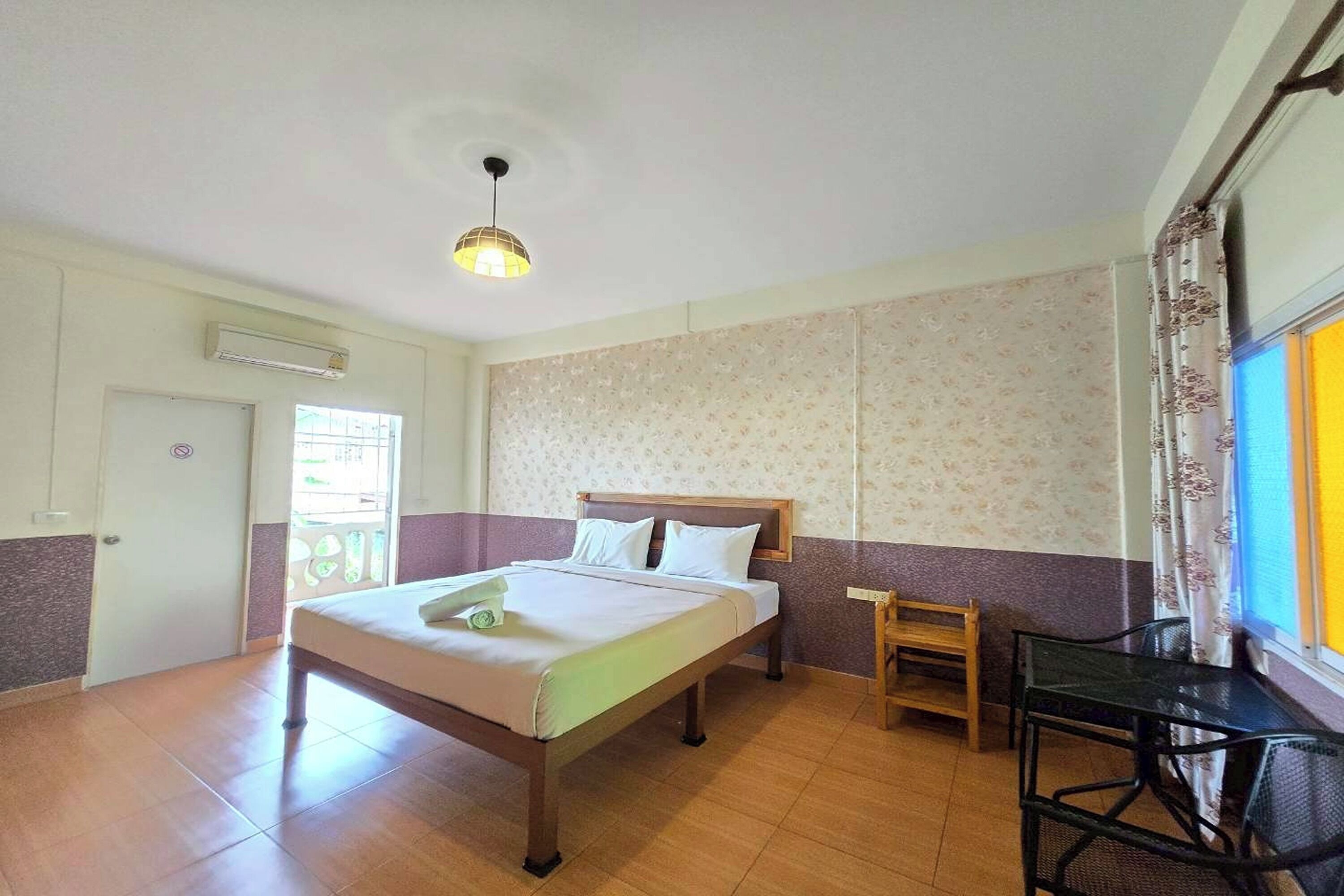 Quarto de hotel com cama, uma mesa pequena e uma cadeira.