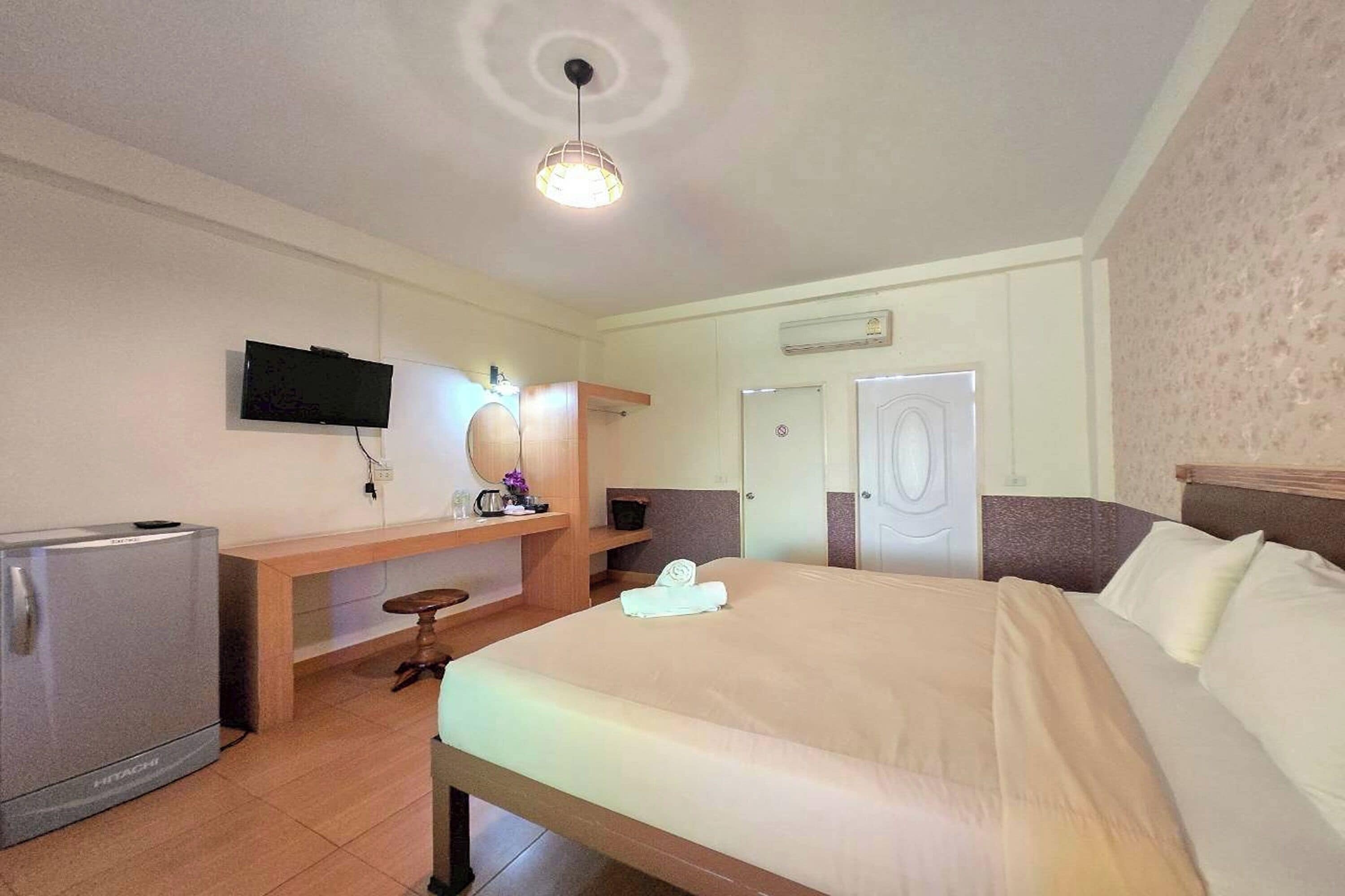 Et hotelværelse med seng, fjernsyn, minibar, skrivebord med stol og dør.