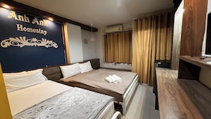 Quarto de hotel com duas camas, uma secretária de madeira, ar condicionado fixado na parede e cortinas.