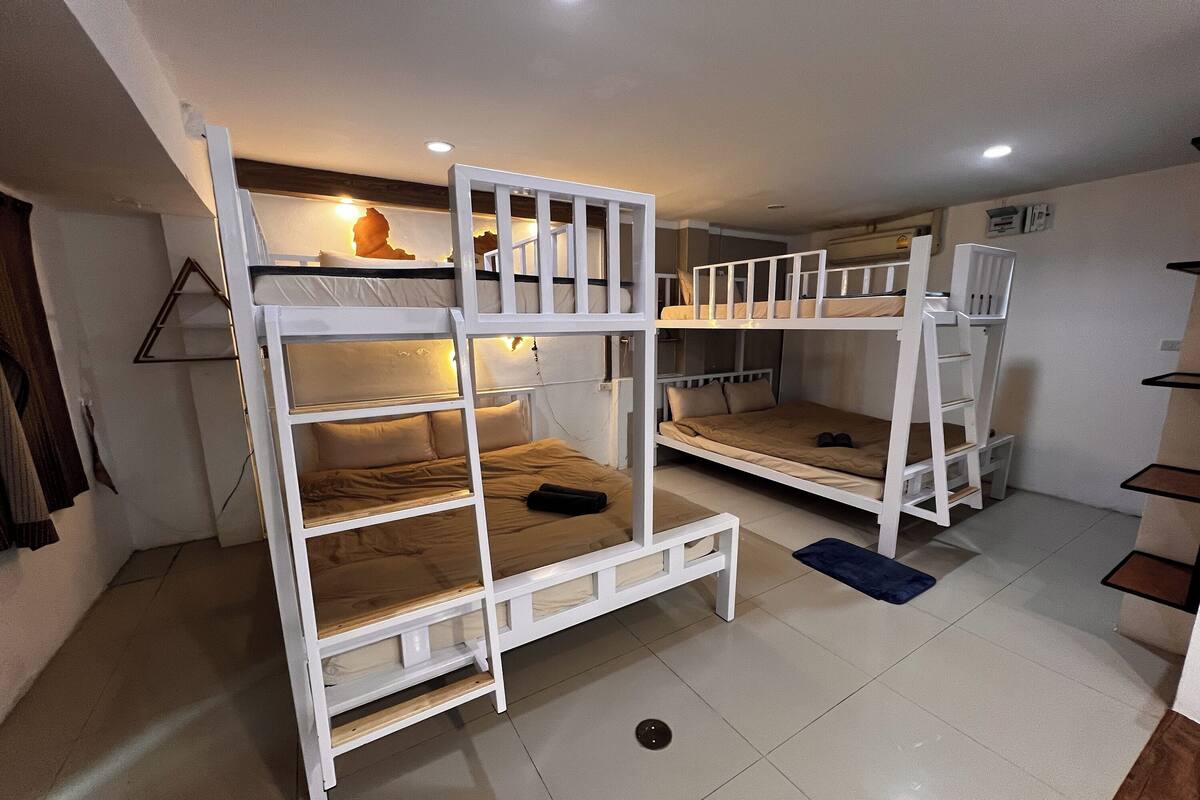 A dormitory room with bunk beds, a small shelf with a statue, and a light fixture above the beds.