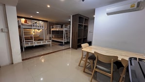 Quarto com beliches, uma mesa de jantar com cadeiras e um ar condicionado.