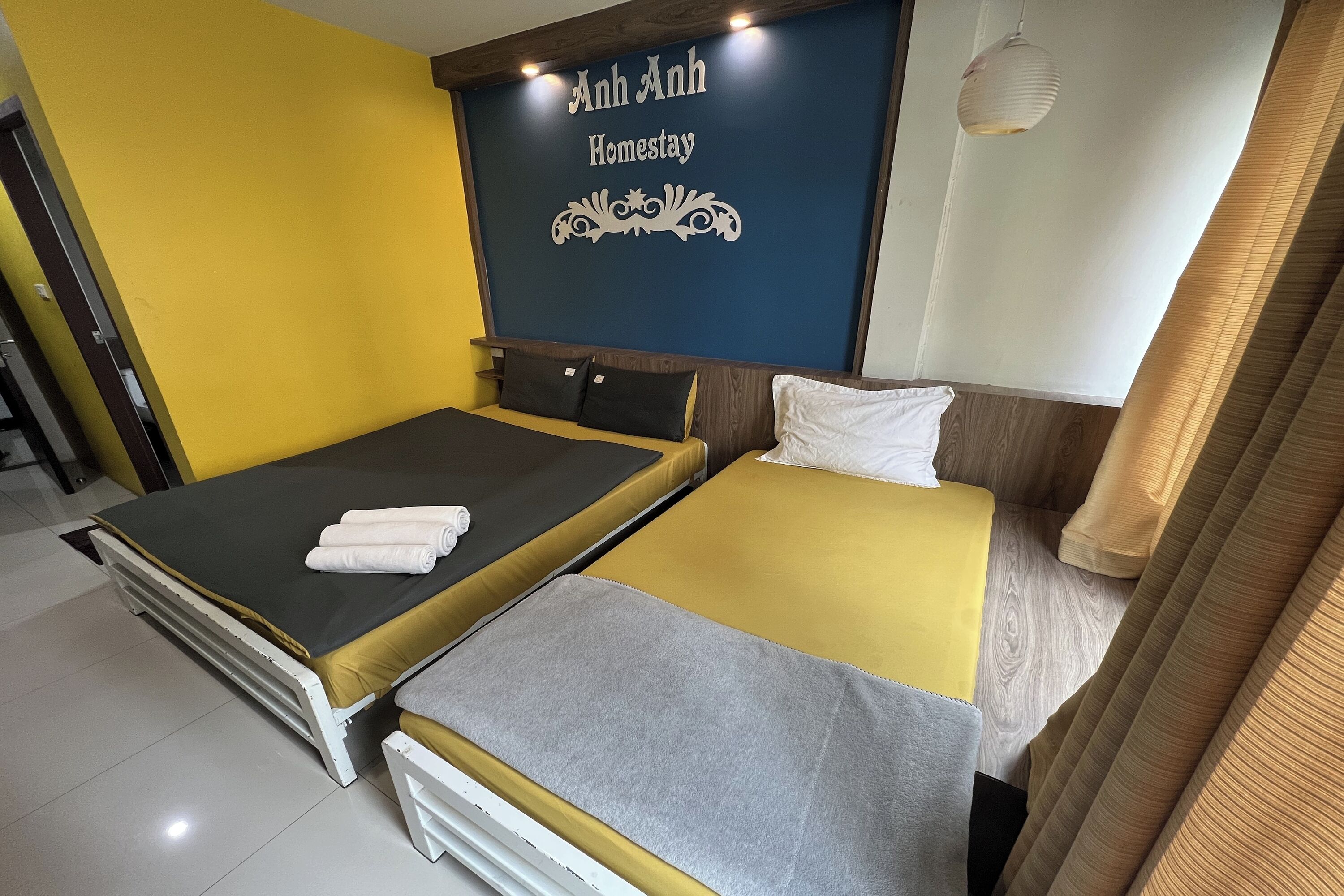 A double bed with a yellow and grey bedspread, a white pillow, and a neatly folded towel.