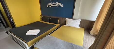 A double bed with a yellow and grey bedspread, a white pillow, and a neatly folded towel.