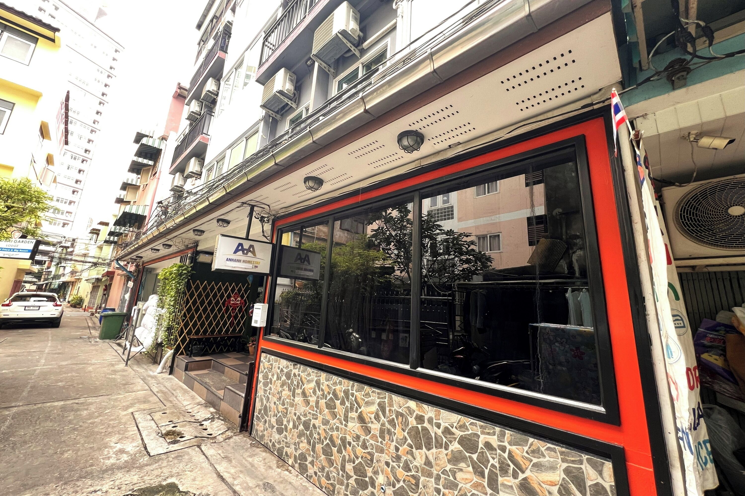 A building with a stone facade, a red and black window frame, and a sign for 'Anjuman Hospital'.