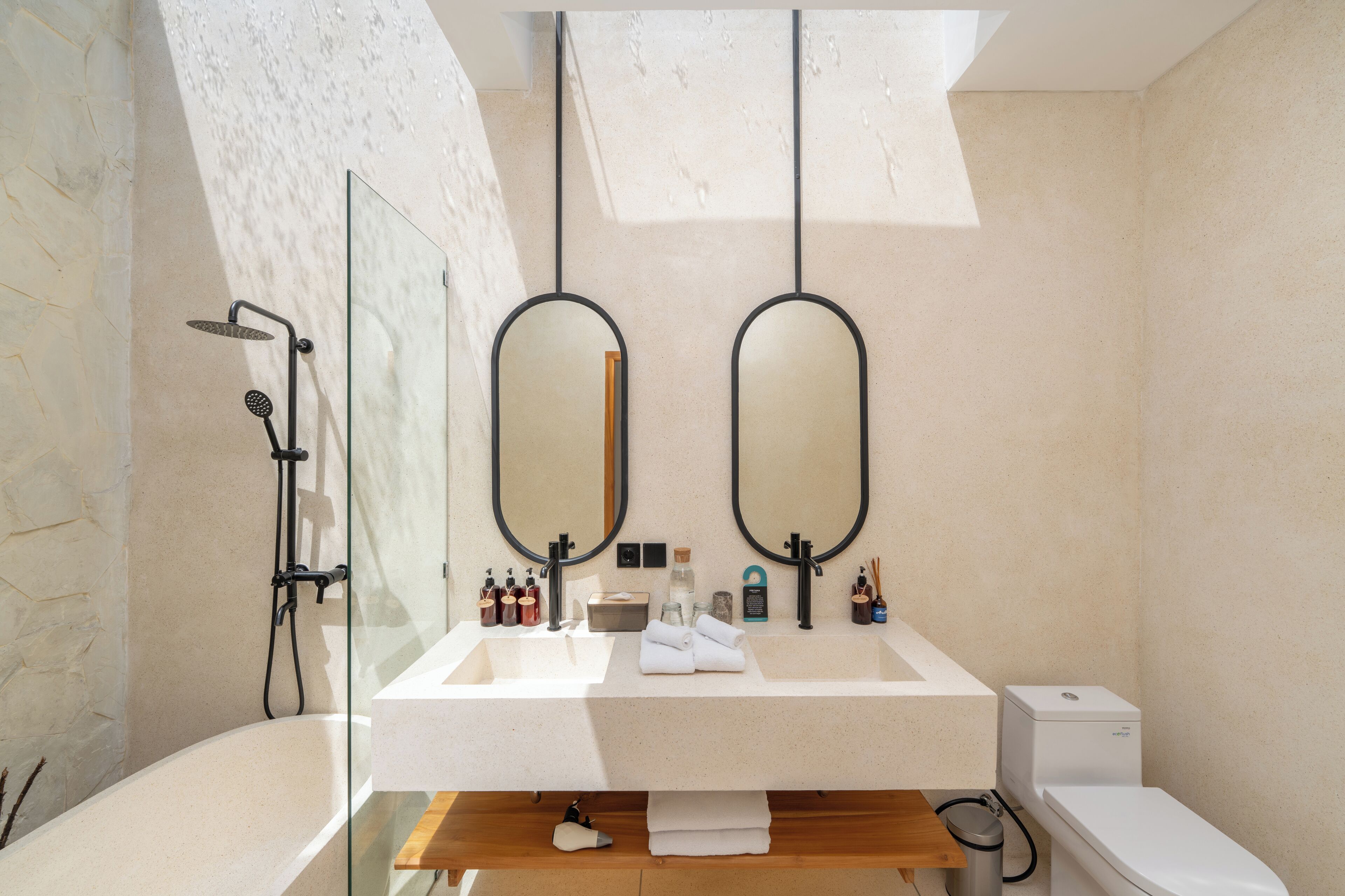 A modern bathroom with a freestanding bathtub, a double vanity with two mirrors, and a toilet.